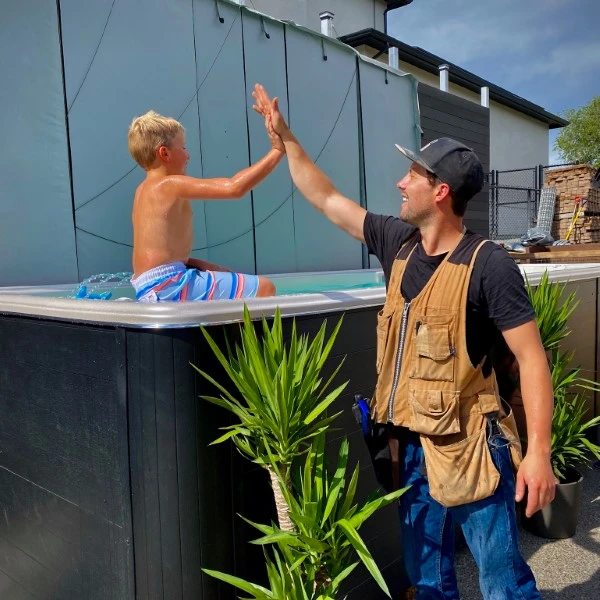 Wangler Electric technician high-fiving child after safe backyard pool and spa electrical installation