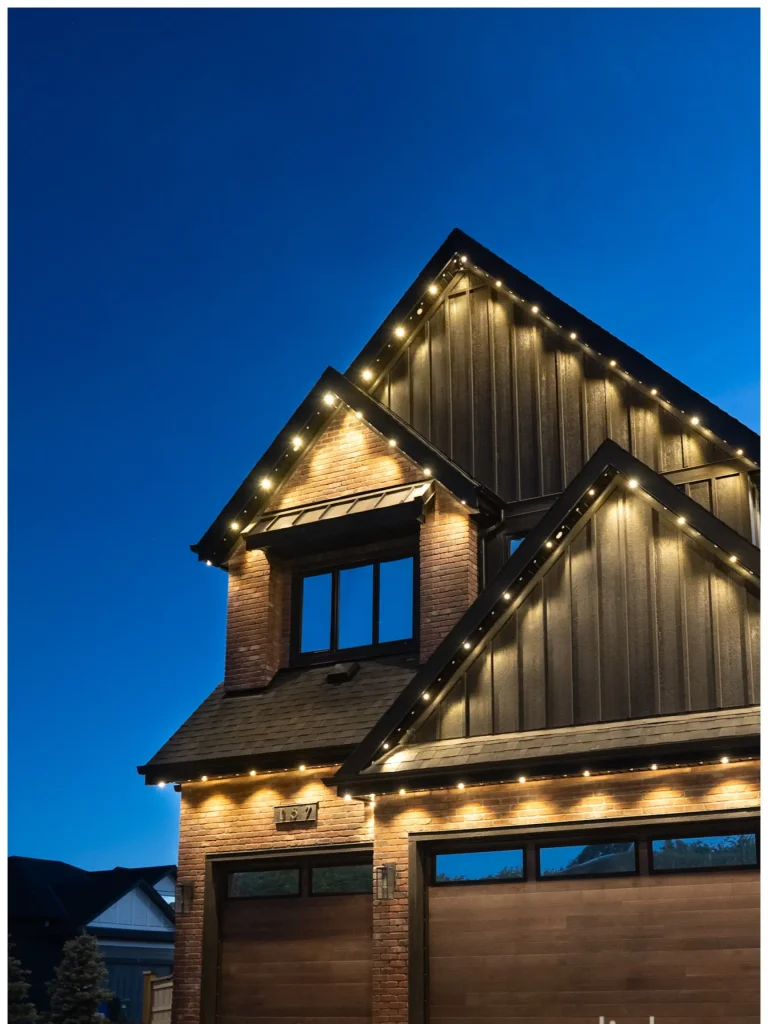 Gemstone lights illuminate a charming modern home under a twilight sky