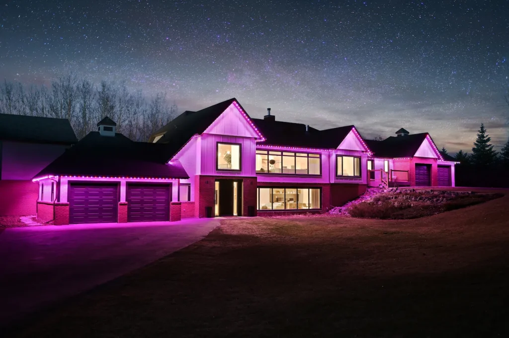 Gemstone lights illuminate a modern house under a starry night sky